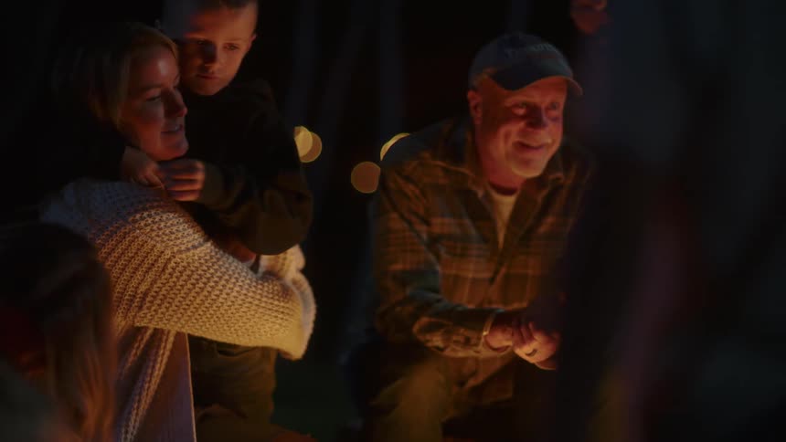 Family smiling hugging sitting around a campfire at night