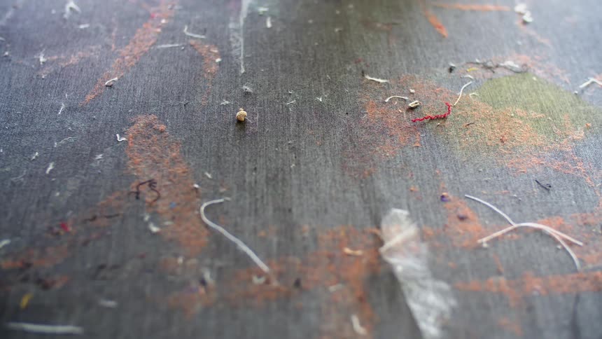 On a wooden surface is scattered bits of string and dust