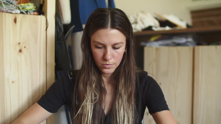 Long haired woman folding clothes in a room at home