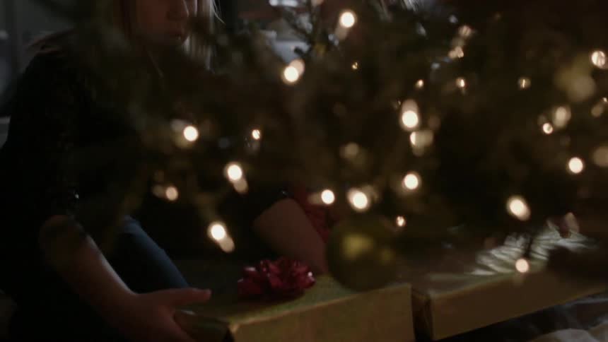 A child is placing presents under a christmas tree