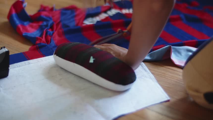 A woman uses an oval shape form to cut a piece of fabric