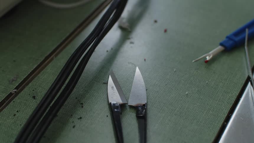 Small knives and a stitch remover sit on a green table