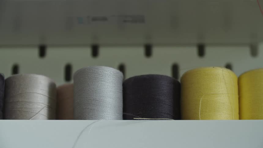Silver beige yellow and black thread spools on a shelf