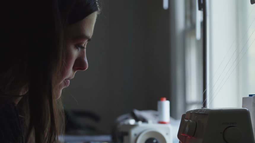 Woman focused on using a sewing machine at home