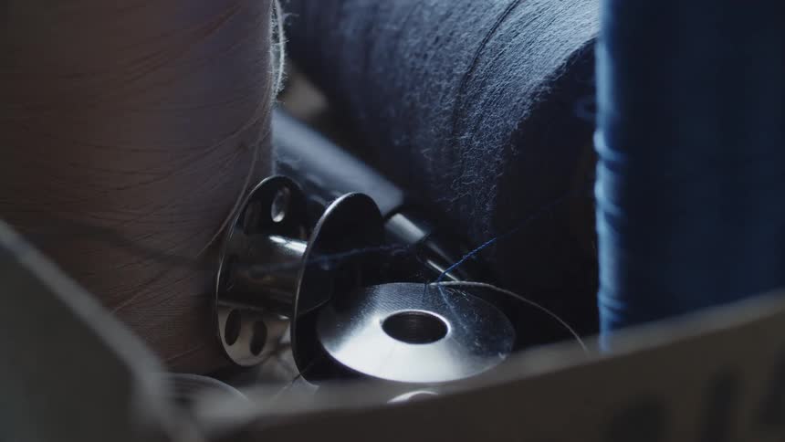 A close up of metal spools and bulk blue and grey thread