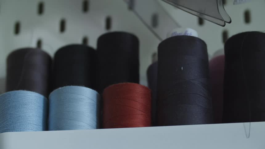 Red blue and black thread spools on a shelf