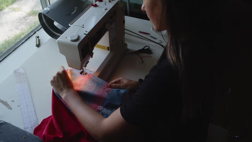 Woman stitching clothes on a sewing machine at home