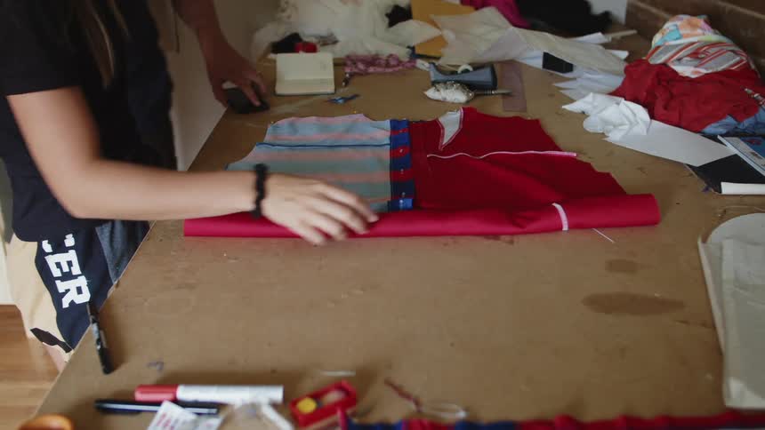 Woman in a home workshop rolling a piece of fabric on a table