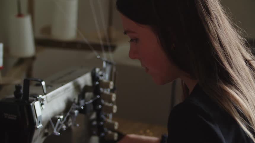 Woman in front of industrial sewing machine using it