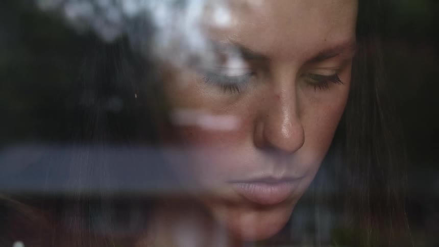 A woman is standing by a window