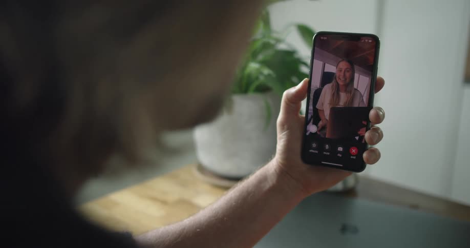Man with long hair and black sweater makes a video call with a woman showing a map on her laptop