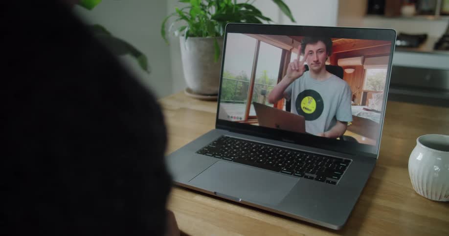 A pair of men gesture at one another through a video chat