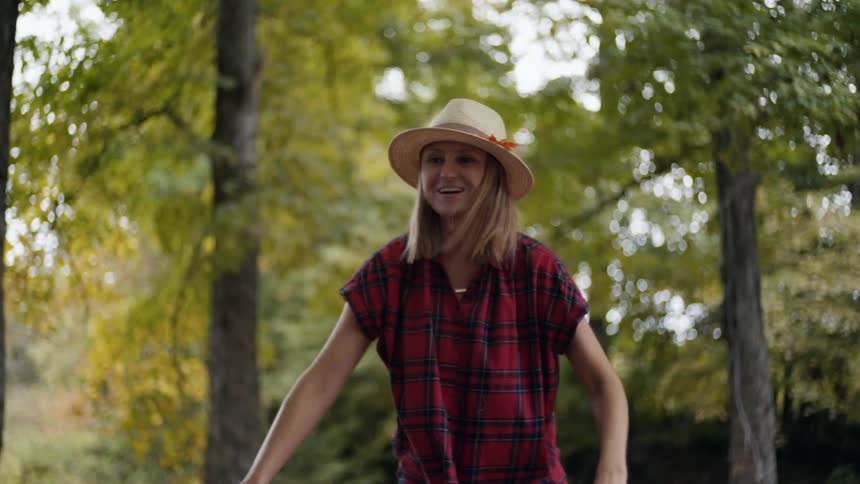 A woman stands outside near trees pushing a girl on a swing