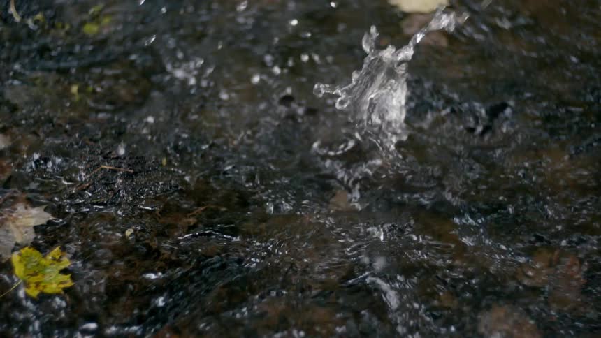 A rock falling into flowing stream water