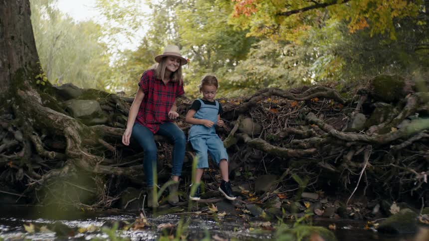 Mother and daughter throwing pebbles on a small creek in the forest