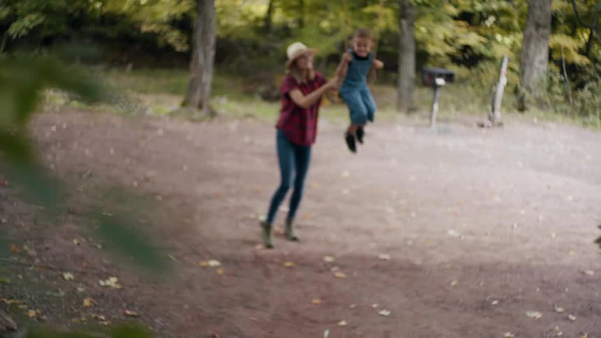 Mother pushing laughing daughter on a tree swing outdoors