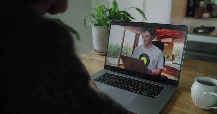 A man sitting at a table with plants in front of a laptop