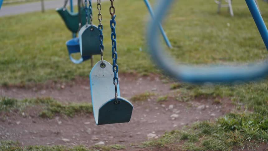 An empty playground with blue swings during lockdown