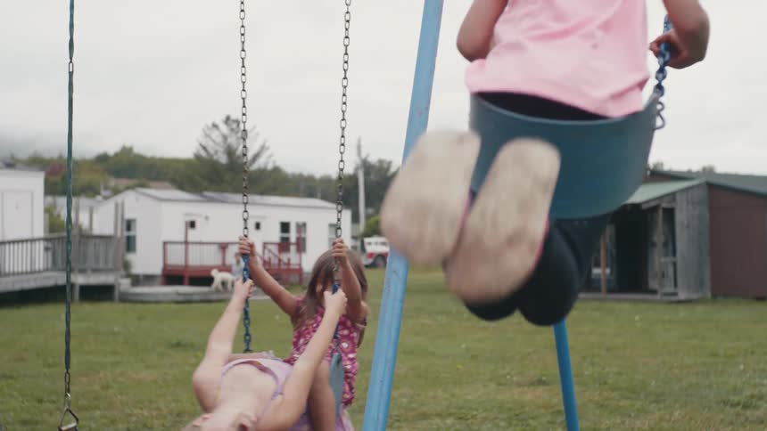 Three young girls swing in a neighborhood playground