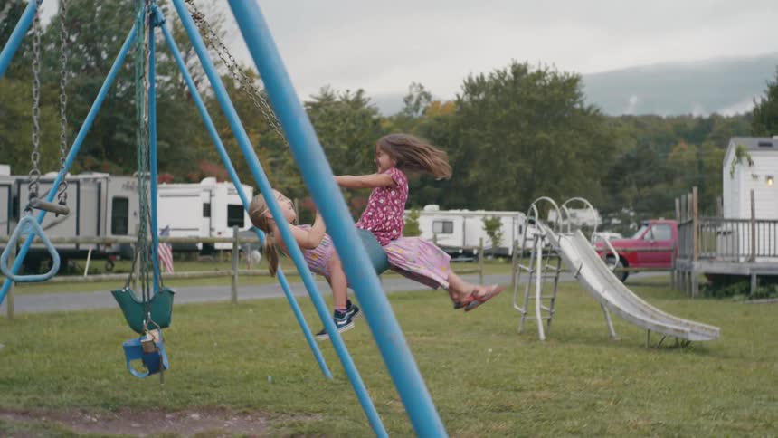 Girls swinging on the swings in the playground in a trailer park