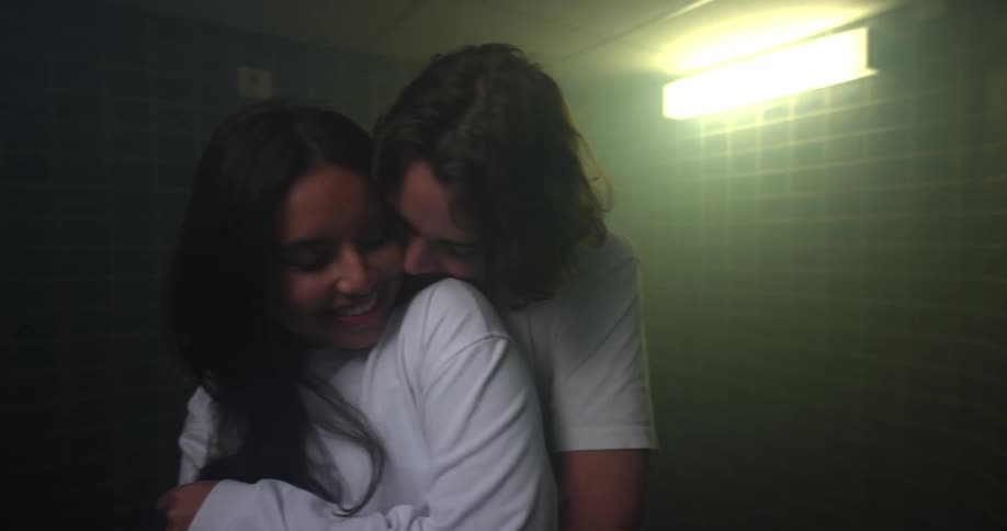 Man hugging a woman from behind in a bathroom while she smiles