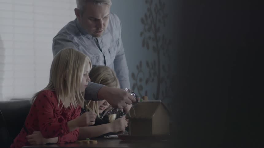 A man decorates a gingerbread house