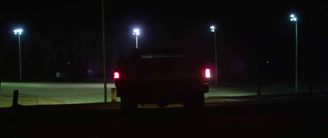 A pickup truck is parked and sits idly in the nighttime darkness