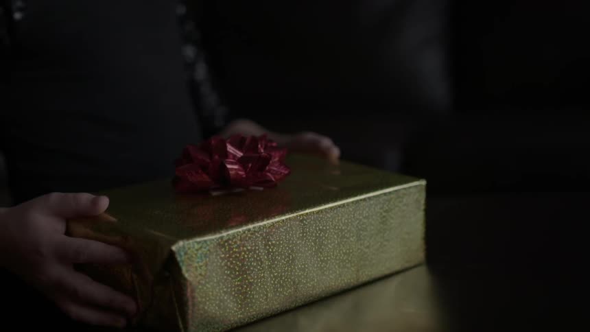 Child picking up a wrapped present off of a table