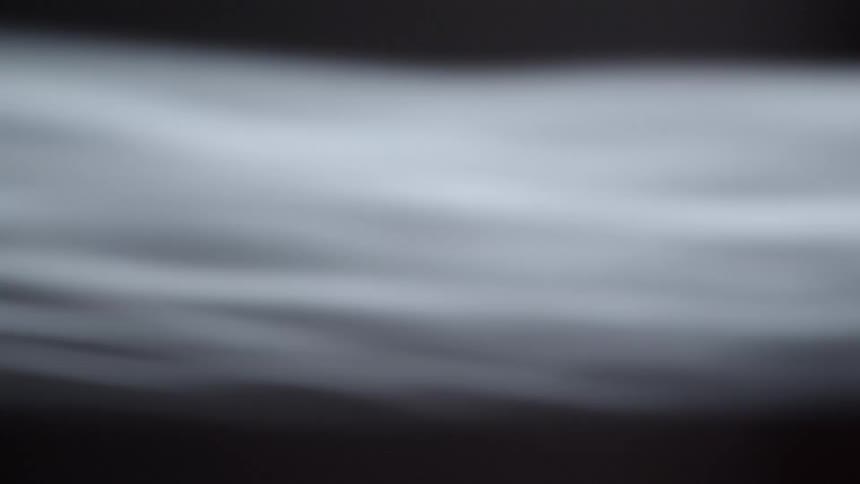 Within the darkness a light fluid like projection wavers against the background