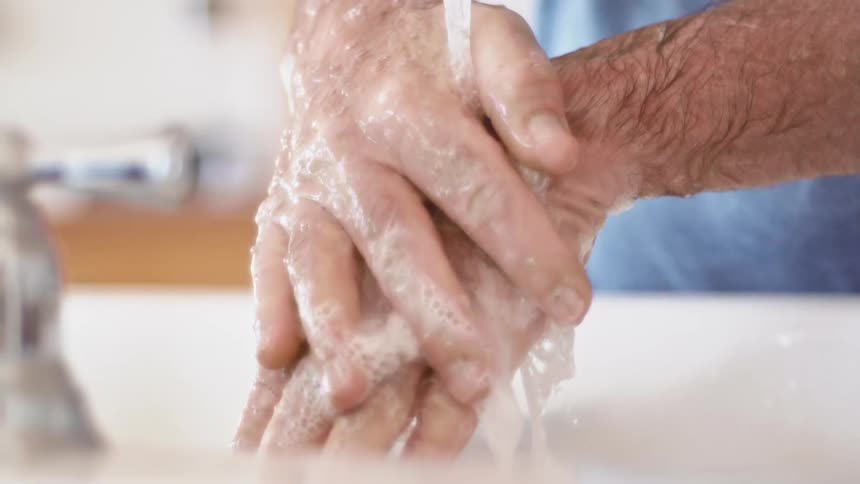 Man washing hands with soap in a sink on the bathroom