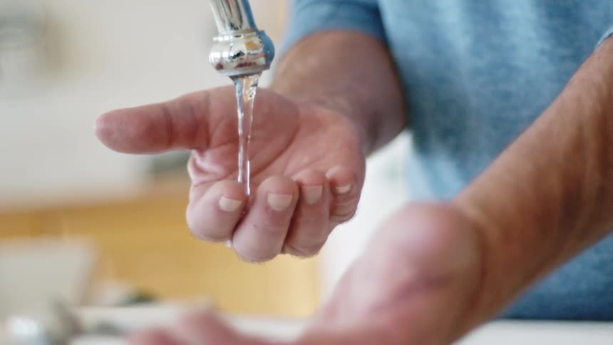 A person washing their hands in a sink in the kitchen