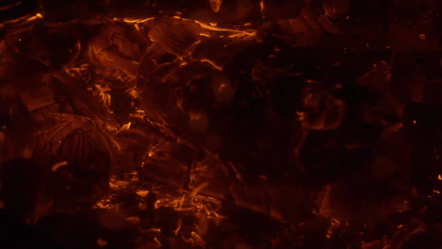 Fire burnt down to embers with sparks and embers floating up and away
