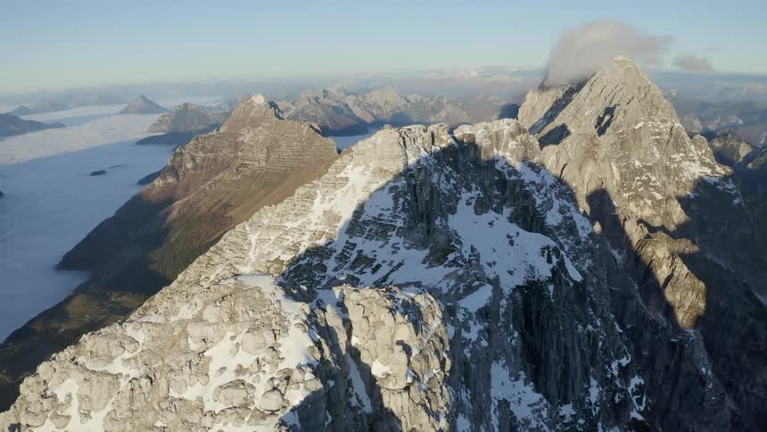 Aerial view of grey mountain peaks covered in white snow at daytime