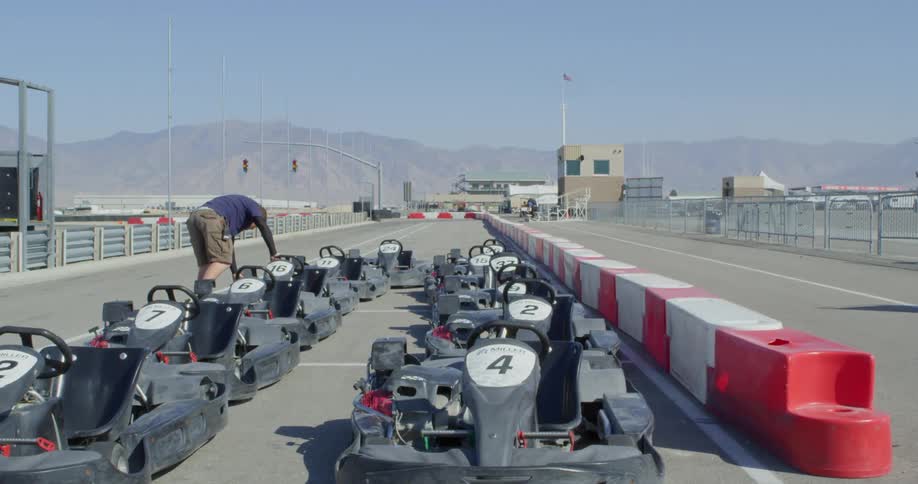 Man pulling the string of a gasoline engine on a go kart in a race track
