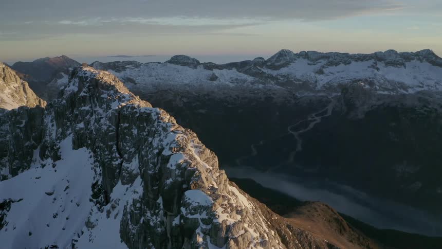 Snow covered mountains are displayed at dusk