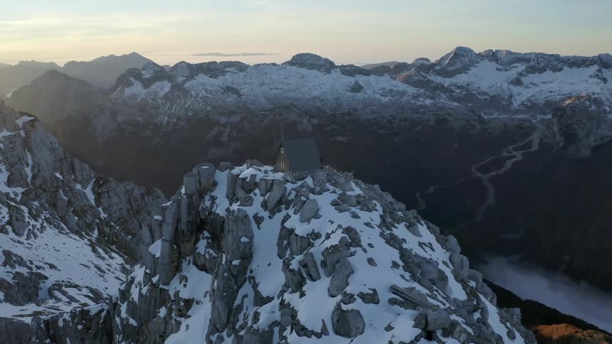 Snowy mountain peaks with a cabin at the very top at day break