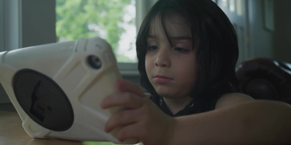 Little girl sitting at table uses a tablet with case