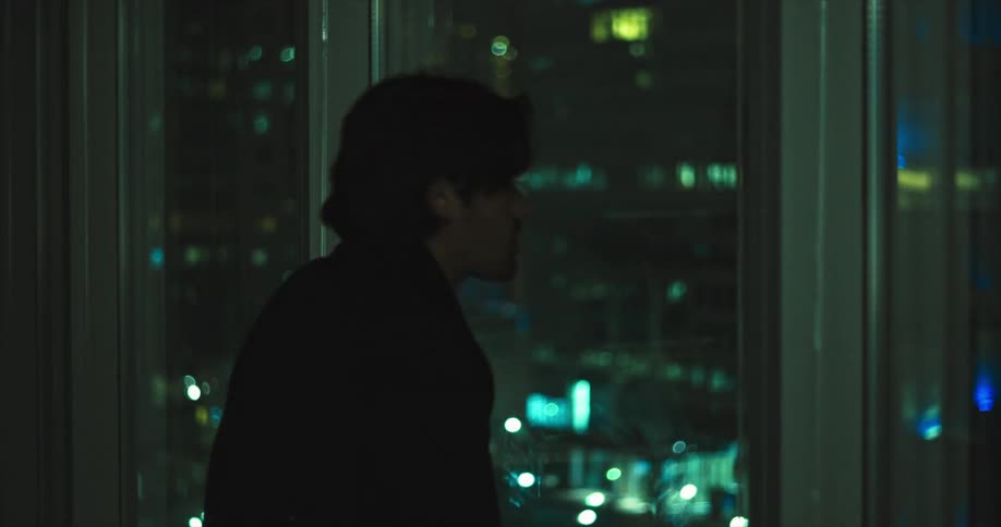 A man somberly looking out a window