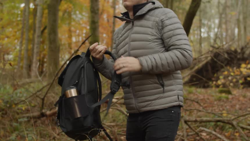 A hiker stops in a forest and puts his backpack on the ground