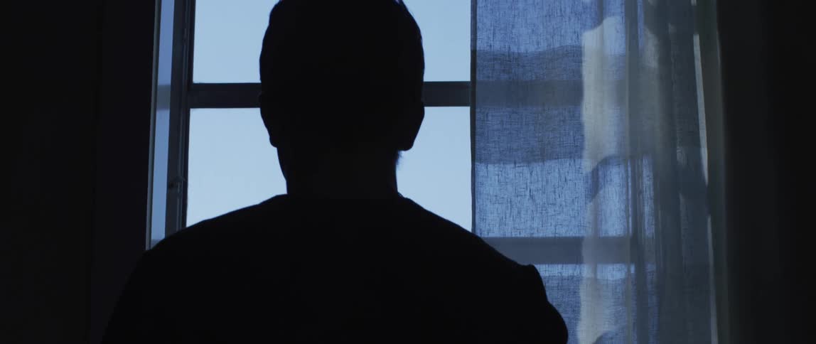 A man standing near a window looking outside