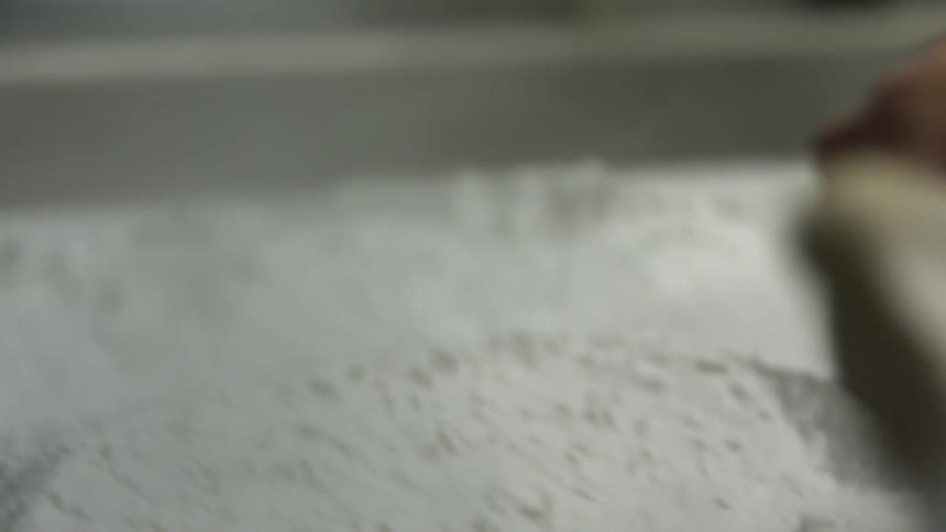 Hand using a bristle brush to move around white powder