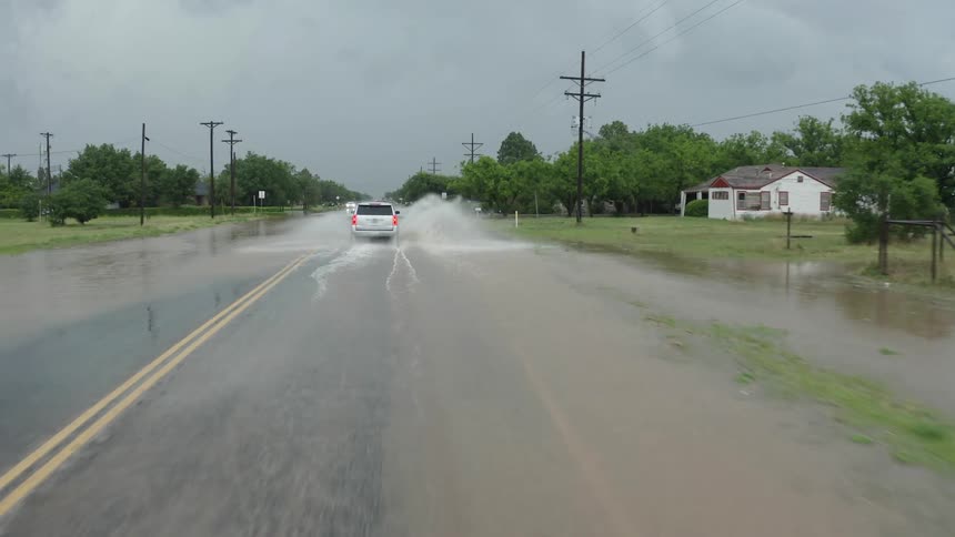Aerial shot following a silver SUV down a flooded roadway in rural America after a huge thunderstorm