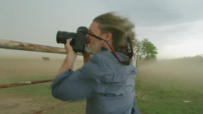 Severe storm high velocity supercell winds blow a photographer nearly over as he documents extreme blowing sand and dust in tornado alley