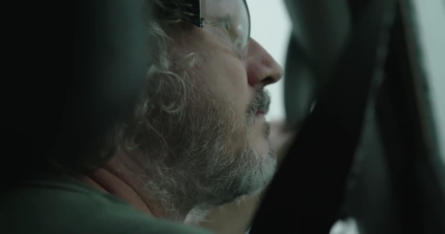 Heavy hail pounds the storm chasing vehicle and a middle aged man wears safety glasses to protect his eyes should the windshield or side window break from a hail strike