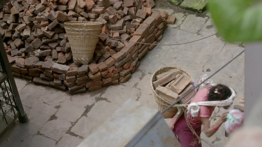 A person is carrying a basket full of bricks