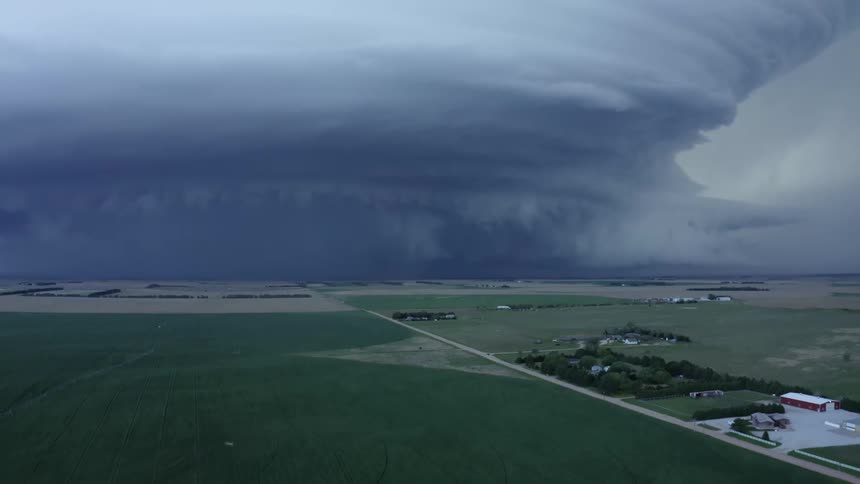 Aerial tilt up shot of the Imperial Nebraska Mothership supercell severe weather thunderstorm as it rolls across and absorbs rural farm land