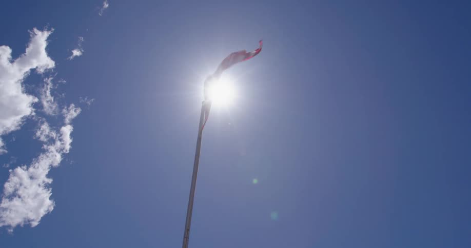 An American flag fluttering in the wind being backlit by the sun blows furiously before storms hammer the region later in the day