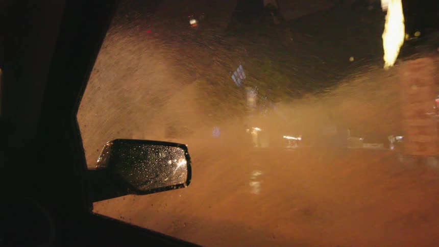 Looking out the window as the vehicle splashes through road flooding as water sprays high above the vehicle