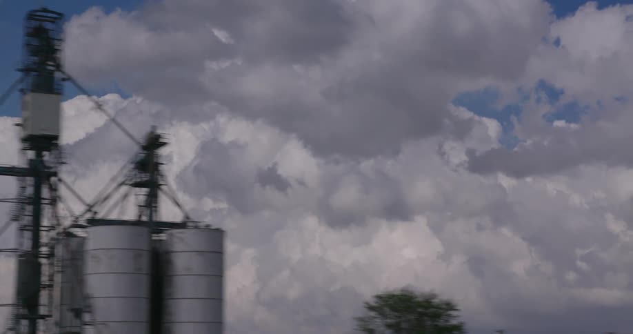 Passenger of a vehicle POV of grain silos and building thunderstorm clouds in this real time shot