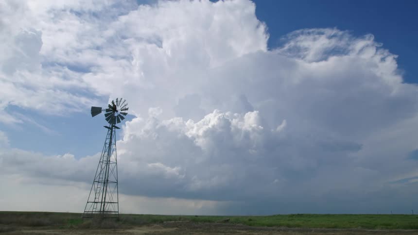 Time lapse of a huge severe thunderstorm building and exploding upward into the sky with an old windmill silhouetted in the foreground